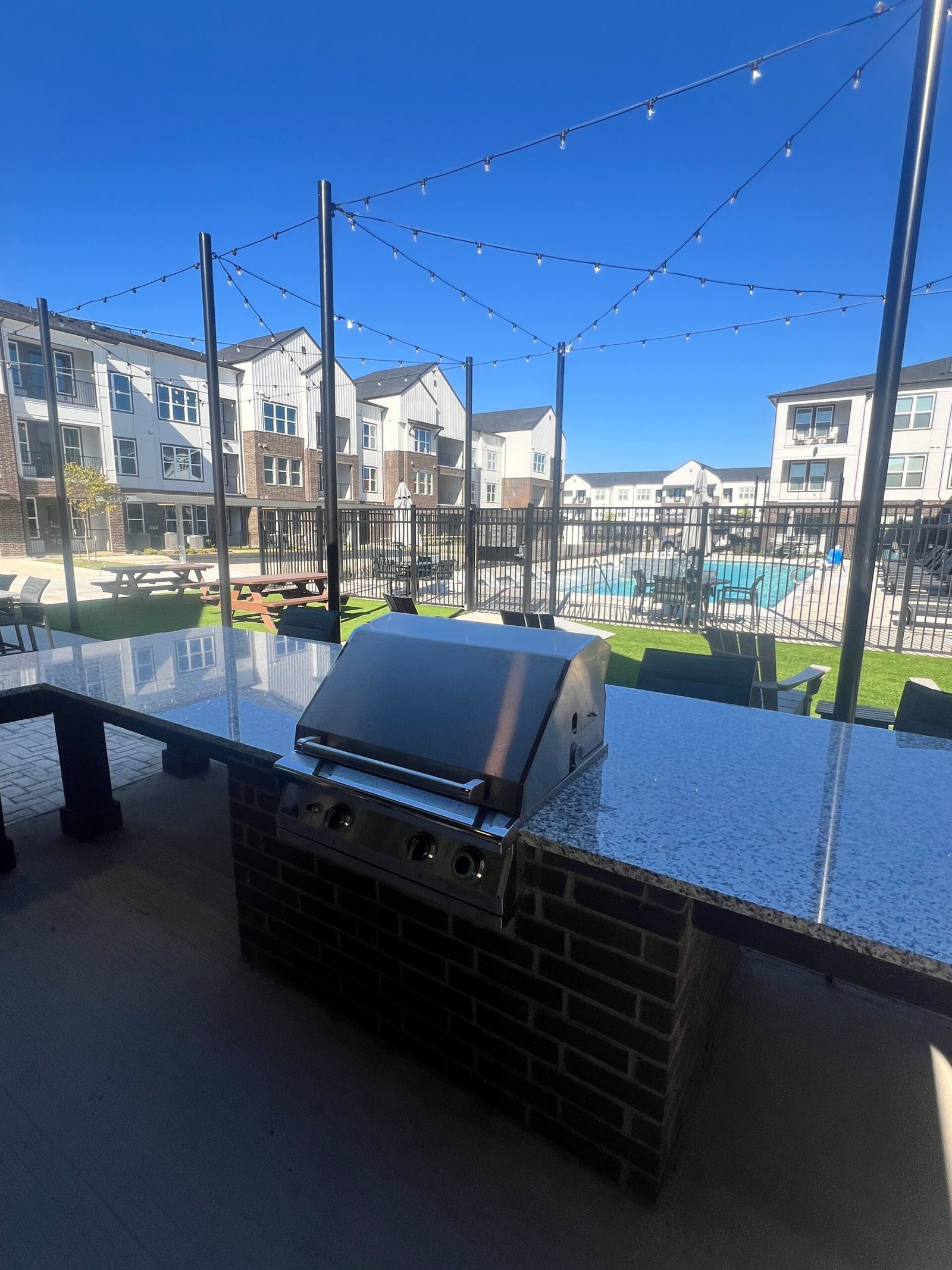 Multifamily grill station overlooking rooftop pool amenity area at a Texas apartment community