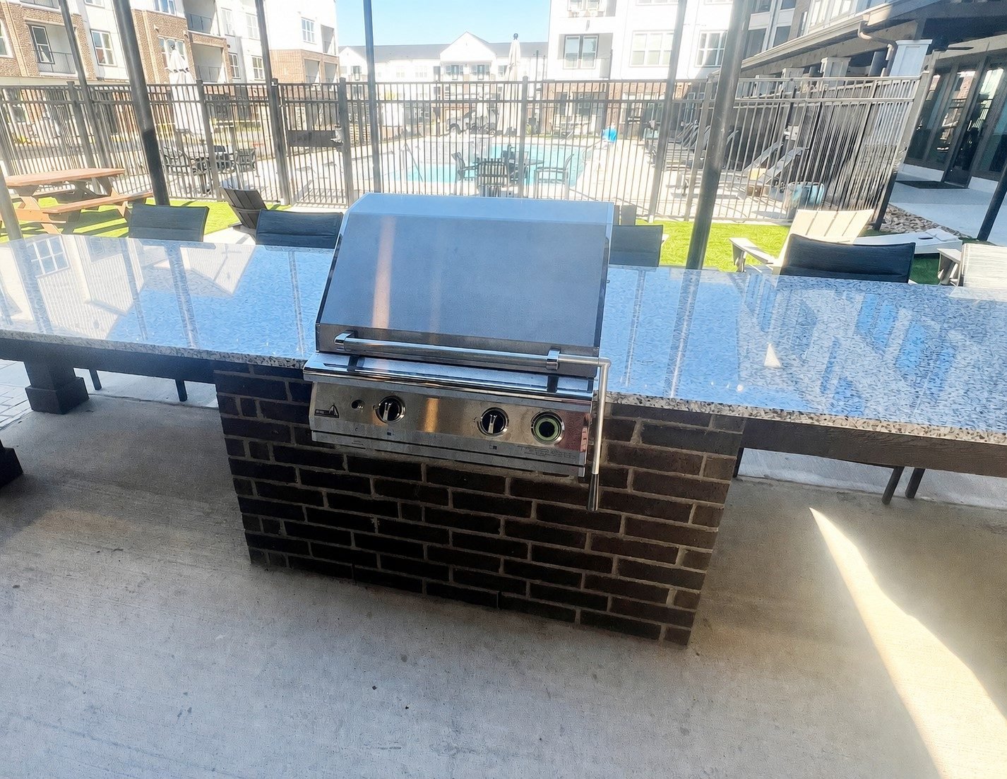 Built-in grill with a side-mounted lift handle and front-mounted controls in the ADA compliant outdoor kitchen at Aspire Apartments in Sherman, TX
