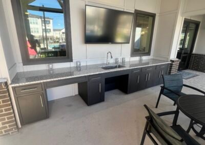 Brick-base built-in gas grill with long granite bar overlooking the pool at a multi-family community. Project: Majestic ADA Design. Builder: Majestic Outdoor Kitchens