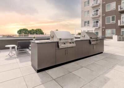 Wide view of Revere, MA rooftop multi-family outdoor kitchen with Danver stainless steel cabinetry at sunset. Project: Revere Rooftop Kitchen. Builder: Danver Outdoor Kitchens