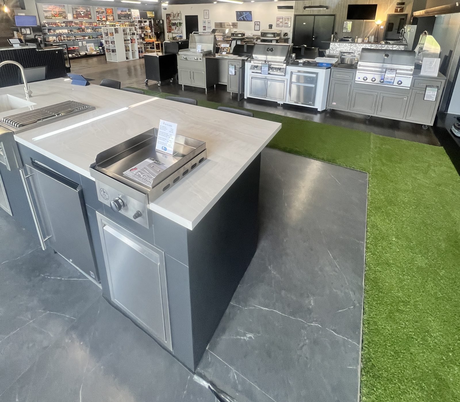 Le Griddle built into a showroom outdoor kitchen island with grills and cabinets on display behind it