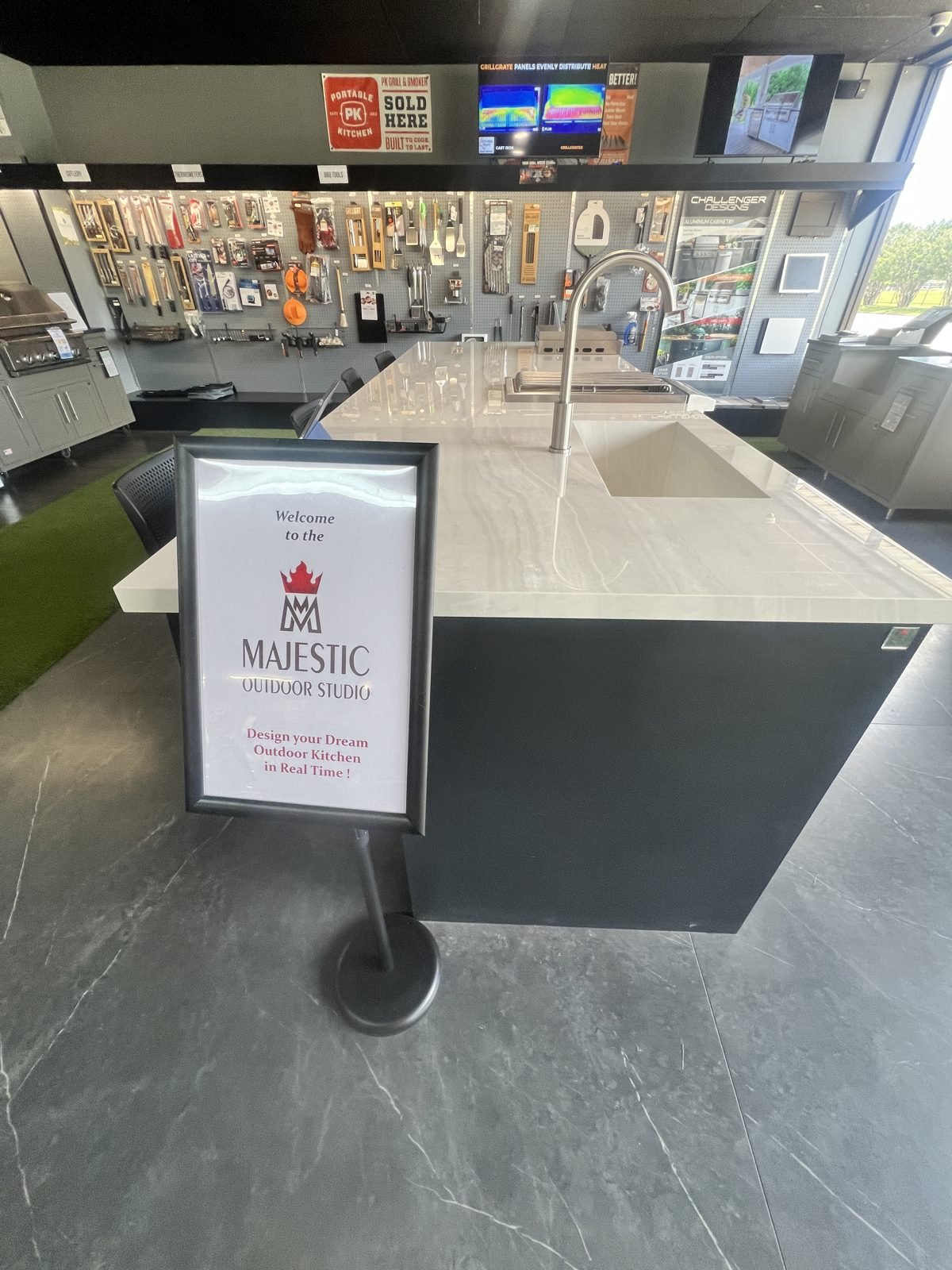 Majestic Outdoor Kitchens welcome sign beside a showroom outdoor kitchen island