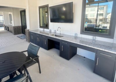 Completed Majestic ADA Design multi-family outdoor kitchen with black cabinets, granite counter, accessible sink and TV. Project: Majestic ADA Design. Builder: Majestic Outdoor Kitchens